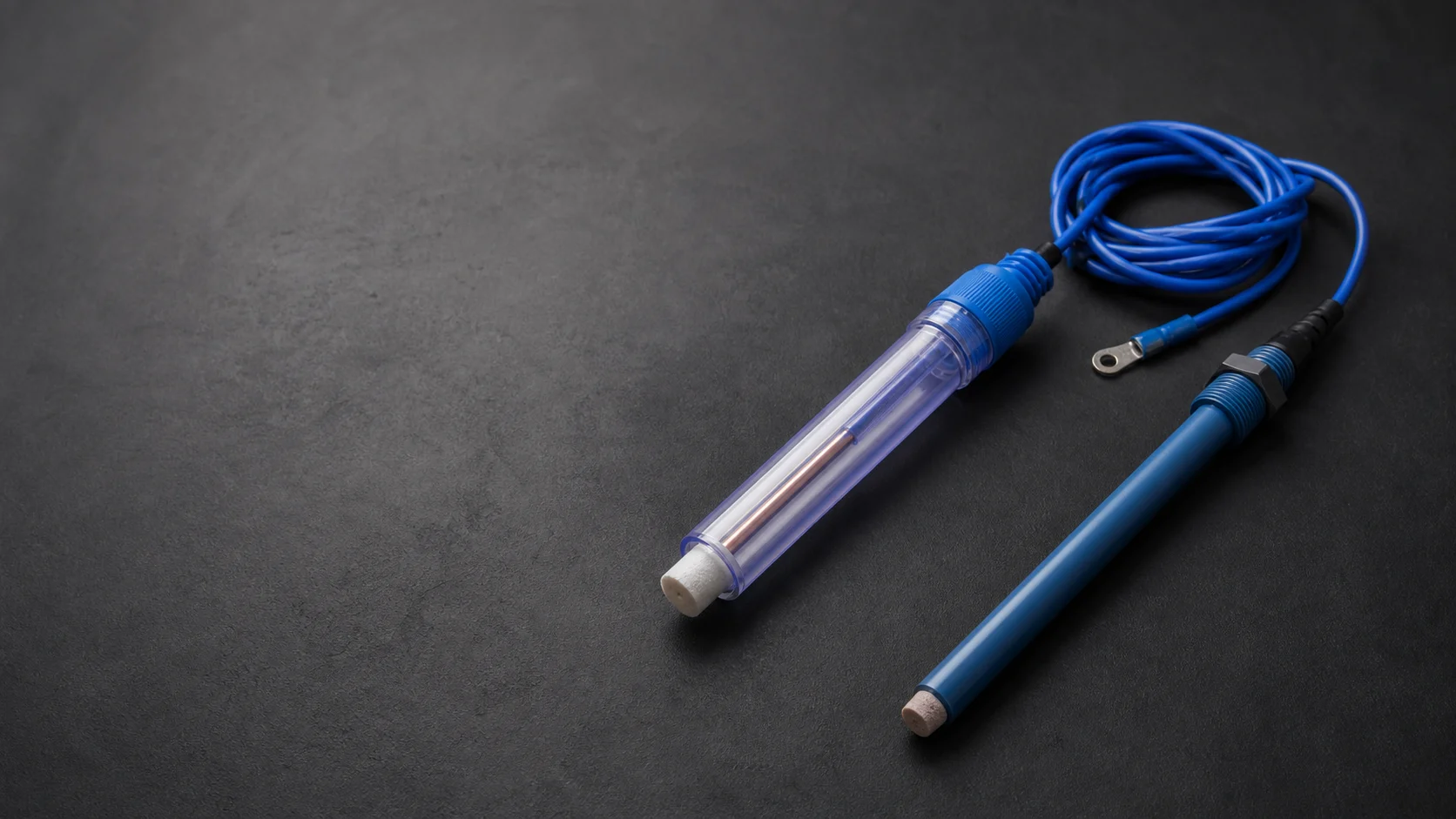 Permanent reference electrodes with blue cables on a dark studio background